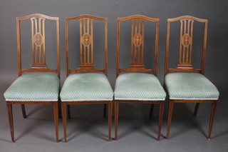 A set of 4 Edwardian inlaid mahogany stick and rail back dining chairs with upholstered seats on square tapering supports