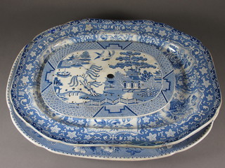 A 19th Century blue and white pottery meat plate decorated a  city with camels - cracked 21", a 19th Century blue and white  meat plate decorated a basket of flowers 20" - cracked and a blue  and white Willow patterned straining platter 14" - cracked