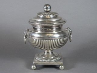 A Continental white metal urn and cover with demi-reeded  decoration and lion mask handles, raised on bun feet 9"