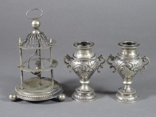 A white metal cocktail stick stand? in the form of a bird cage 3" together with 2 embossed white metal twin handled urns 3 1/2"