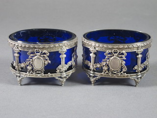 A pair of pierced white metal oval salts complete with blue glass liners 3"