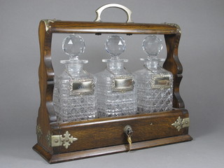 An oak and silver mounted 3 bottle tantalus fitted 3 hobnail cut  decanters and stoppers, complete with silver plated labels   ILLUSTRATED