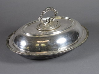 An oval silver plated entree dish and cover with bead work  border