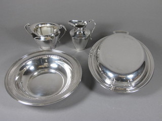 An oval silver plated entree dish and cover, a circular bowl, a  silver plated cream jug and sugar bowl