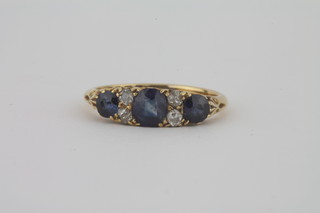 A lady's 18ct gold dress ring set oval cut sapphires supported by diamonds