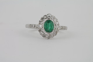 A lady's 18ct white gold dress ring set an oval cut emerald  surrounded by diamonds