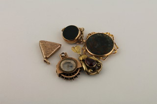 A 9ct gold fob in the form of a compass, a gilt metal pendant, a 9ct gold revolving seal, a gilt metal locket and a gilt metal  pendant set a cabouchon cut stone