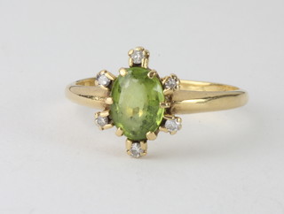 A yellow gold dress ring set an oval cut peridot supported by  diamonds