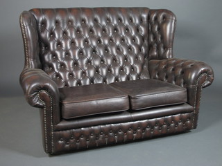 A 19th Century style brown leather buttoned wing back settee, fitted loose cushions, raised on casters 55"w