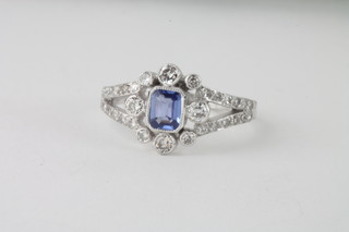 An 18ct white gold dress ring set a rectangular sapphire  supported by diamonds and with diamonds to the shoulders
