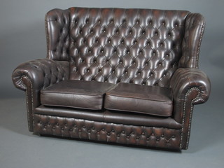 A 19th Century style brown leather buttoned wing back settee, fitted loose cushions, raised on casters 55"w