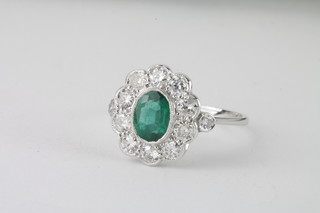 An 18ct white gold dress ring set an oval emerald surrounded by  diamonds