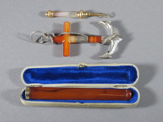 An amber and gold mounted cheroot holder, a polished hardstone brooch in the form of an anchor and a polished hardstone button  hook