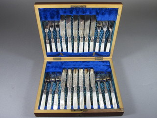 An Edwardian canteen of 12 silver plated fruit knives and forks  with mother of pearl handles in a walnut canteen