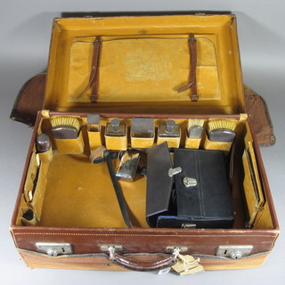 A fitted leather vanity case containing 4 glass bottles with silver tops together with a pair of military backed hair brushes, clothes  brush and a shaving brush holder, Birmingham 1934 with Jubilee  hallmark,