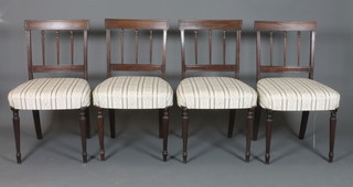 A set of 4 Sheraton style mahogany dining chairs, 19th Century, with tablet cresting rails above foliate carved and reeded spindle  backs, foliate woven stuff-over seats and raised on turned tapered  reeded legs