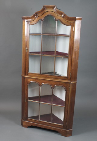An early 19th Century Dutch style walnut standing corner cabinet, having a broken arch moulded cornice above a pair of  bar glazed doors enclosing shelves, raised on shaped plinth base  71"h x 33"w x 18"d