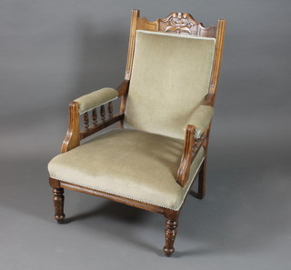 A late Victorian stained beechwood low seat open arm chair  having a foliate carved cresting rail, with pale green dralon  upholstery raised on ring turned tapered legs
