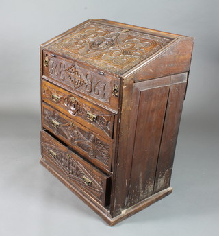 An 18th Century and later oak scribes desk, having foliate and lunette carved decoration, the fall enclosing a fitted an interior  above 3 graduated long drawers on a plinth base 41"h x 32"w x  22"d