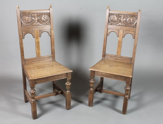 A pair of 17th Century style oak dining chairs, having vineous  relief carved backs, solid seats on reeded turned square legs