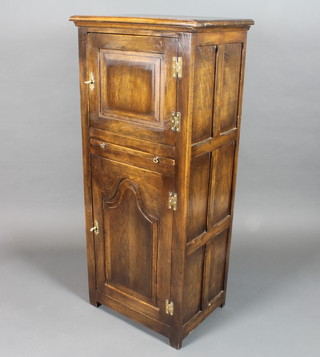 An early 18th Century style oak press cupboard fitted 2 fielded panelled cupboard doors and brushing slide, raised on end stiles  51"h x 22.5"w x 16.5"d
