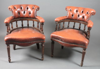 A pair of mahogany Captain's chairs having red leather buttoned upholstery, raised on ring turned tapered legs