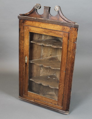 An early 18th Century oak hanging corner cabinet, with broken swan neck pediment above a glazed door enclosing shaped  shelves 45"h x 26"w x 14"d