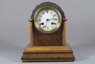 A French 8 day striking mantel clock with enamelled dial and Roman numerals contained in an arch shaped walnut and parcel  ebonised case
