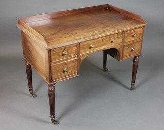 A late Victorian mahogany kneehole writing table with galleried  top above an arrangement of 5 small drawers, raised on ring  turned, reeded tapered legs with brass caps and casters 32"h x  41"w x 23.5"d