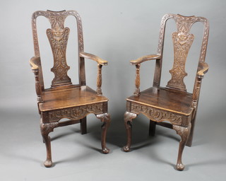A pair of unusual Queen Anne style oak elbow chairs, the vase  splats relief carved with satire masks and scrolls above solid seats  and shaped aprons, raised on cabriole legs pad feet