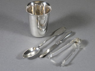 A Continental engraved silver beaker, do. spoon, pair of silver tongs, 2 ozs together with a silver handled manicure implement