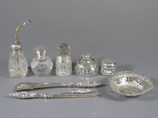A cut glass atomiser with embossed white metal lid, 4 glass dressing table jars with silver lids, a cut glass salt bottle with  silver lid, 2 silver handled button hooks, do. shoe horn and a  pierced silver dish 3.5"