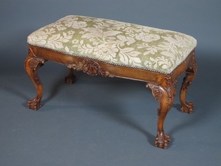 A George II style carved walnut and beech wood dressing stool in  the Irish taste, having floral-cut upholstered seat, the frieze  decorated a honeysuckle scrolled cartouche, raised on foliate  carved cabriole legs, claw and ball feet 19"h x 34"w x 18"d