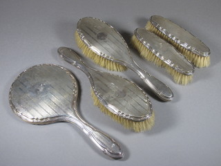 A 5 piece silver backed dressing table set comprising handmirror, pair of hair brushes, pair of clothes brushes