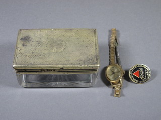 A Victorian rectangular cut glass dressing table jar with silver lid with engine turned decoration containing a wristwatch and a gilt  badge, 3.5", London 1878