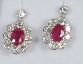 A pair of 18ct gold drop earrings set oval cut rubies surrounded  by diamonds, approx 1.60ct