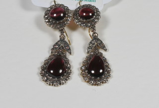 A pair of 18ct gold tear drop shaped earrings set cabouchon cut  garnets supported by diamonds