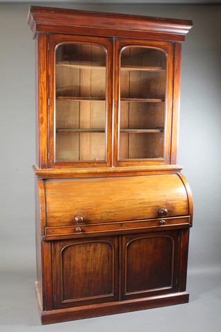 A Victorian mahogany cylinder bureau bookcase, the upper section with moulded cornice, the shelved interior enclosed by  glazed doors, the cylinder fall enclosing a fitted interior above a  pair of cupboards 89"h x 47"w x 22"d   ILLUSTRATED