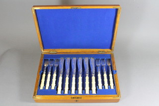 A set of 12 silver plated fish knives and forks with carved ivory handles contained in an oak canteen box