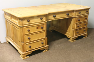 A Georgian style pine kneehole inverted breakfront partners desk,  fitted 2 long and 10 short drawers above a cupboard, raised on  ogee bracket feet 30"h x 70"w x 35"d