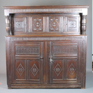 An 18th/19th Century carved oak court cupboard, the upper section with colonnade cornice above a pair of panelled doors with columns to the side, the base with pair of panelled doors 63"h x 63"w x 25"d