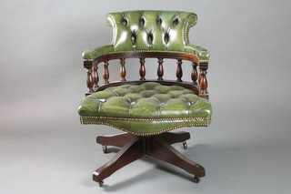 A mahogany revolving tub back office chair upholstered in green buttoned material