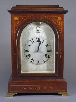 H.A.C. Wurttenberg, an early 20th Century mahogany bracket  clock, the architectural case decorated marquetry bell flowers and  spandrels, raised on brass feet, the arched topped silvered  engraved Roman dial set 8 day movement, chiming 4 gongs,  14"h x 10"w x 7"d
