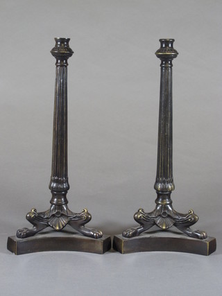 A pair of bronzed Empire style reeded candlesticks, raised on triform bases 11"