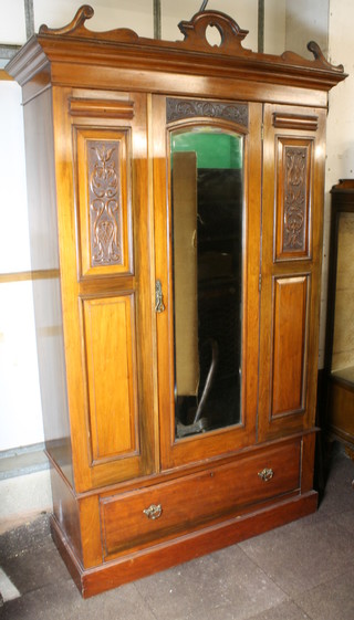 A Victorian carved walnut wardrobe with moulded cornice, the centre section fitted an arch shaped bevelled plate mirrored door  flanked by a pair of carved panels, the base fitted 1 long drawer,  raised on a platform base 51"w x 20"d x 87"h