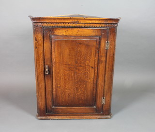An early 18th Century oak hanging corner cupboard with  moulded cornice above a fielded panelled cupboard door enclosing 3 shelves 40"h x 32"w x 16"d