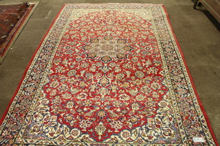 A North West Persian Isphahan style carpet, the red ground  foliate field quartered and centred with an 8 lobed floral motif,  multi bordered and fringed 135"l x 80"w