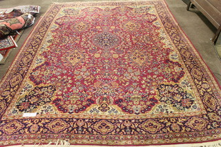 A North West Persian Isphahan style red ground carpet, the field centred with a floral motif and flanked by foliate spandrels, multi  bordered and fringed 140"l x 107"w, cut