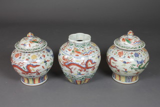 A pair of Oriental baluster shaped urns and covers in polychrome enamels decorated a dragon 12", together with a matching vase  12"