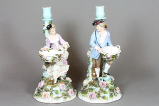 A pair of 19th Century Continental porcelain candlesticks in the form of a standing lady and gentleman with baskets of flowers,  gentleman f and r, 12"